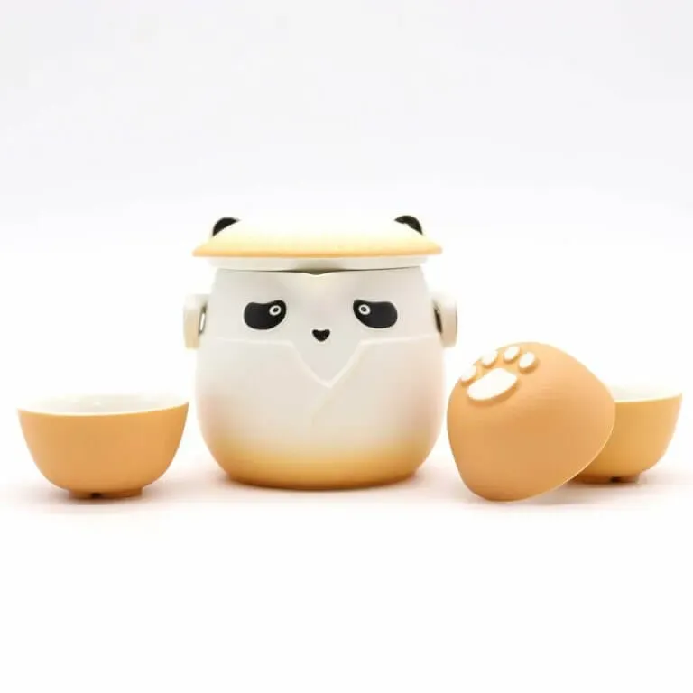 A tea set featuring a panda-shaped teapot with a lid and two matching cups, all with a beige and white color scheme and paw print details.