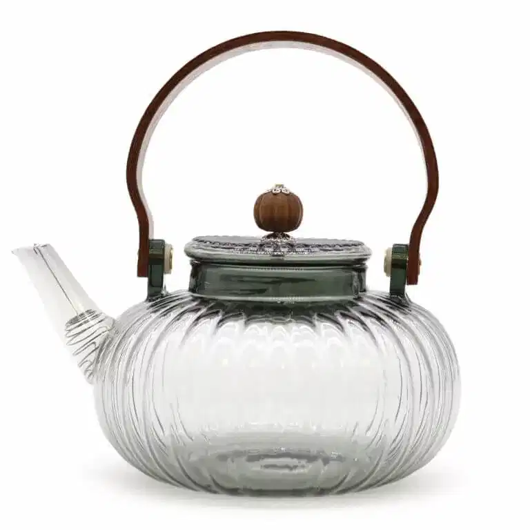 Clear glass teapot with a ribbed design, short spout, metal lid topped with a wood knob, and a curved wooden handle.