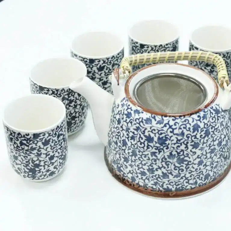 A ceramic teapot with a woven handle and six matching teacups, all featuring a blue and white floral pattern, arranged on a white surface.