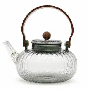 Clear glass teapot with a ribbed design, short spout, metal lid topped with a wood knob, and a curved wooden handle.