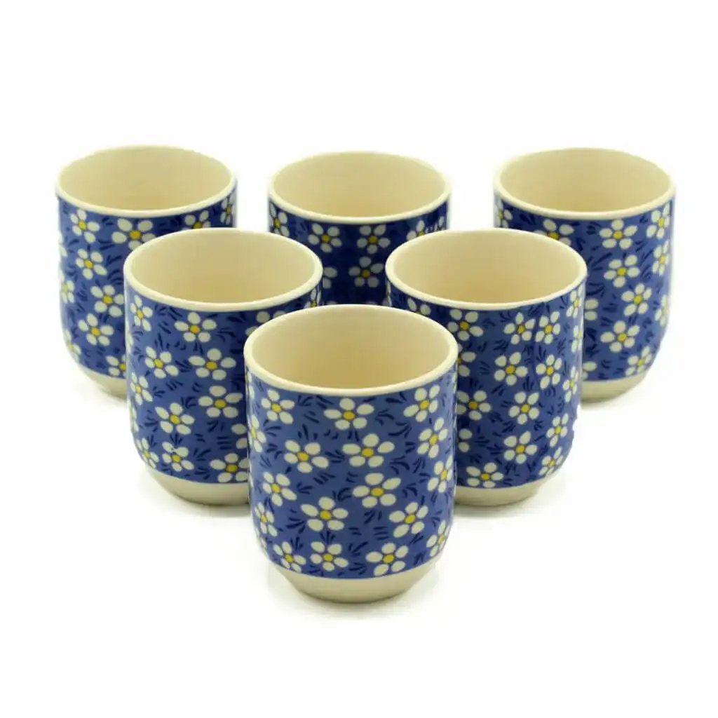 Six ceramic cups with a blue background and white floral pattern arranged in two rows on a white surface.