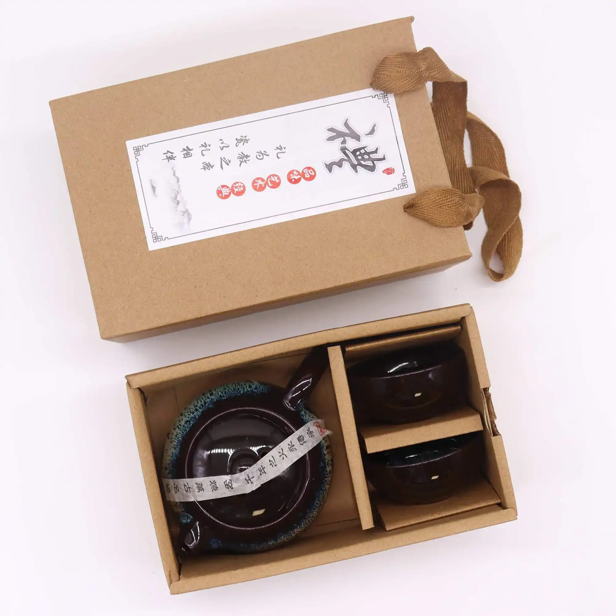 A boxed tea set with a brown ribbon, containing a teapot and two cups, with a label featuring Chinese characters on the lid.