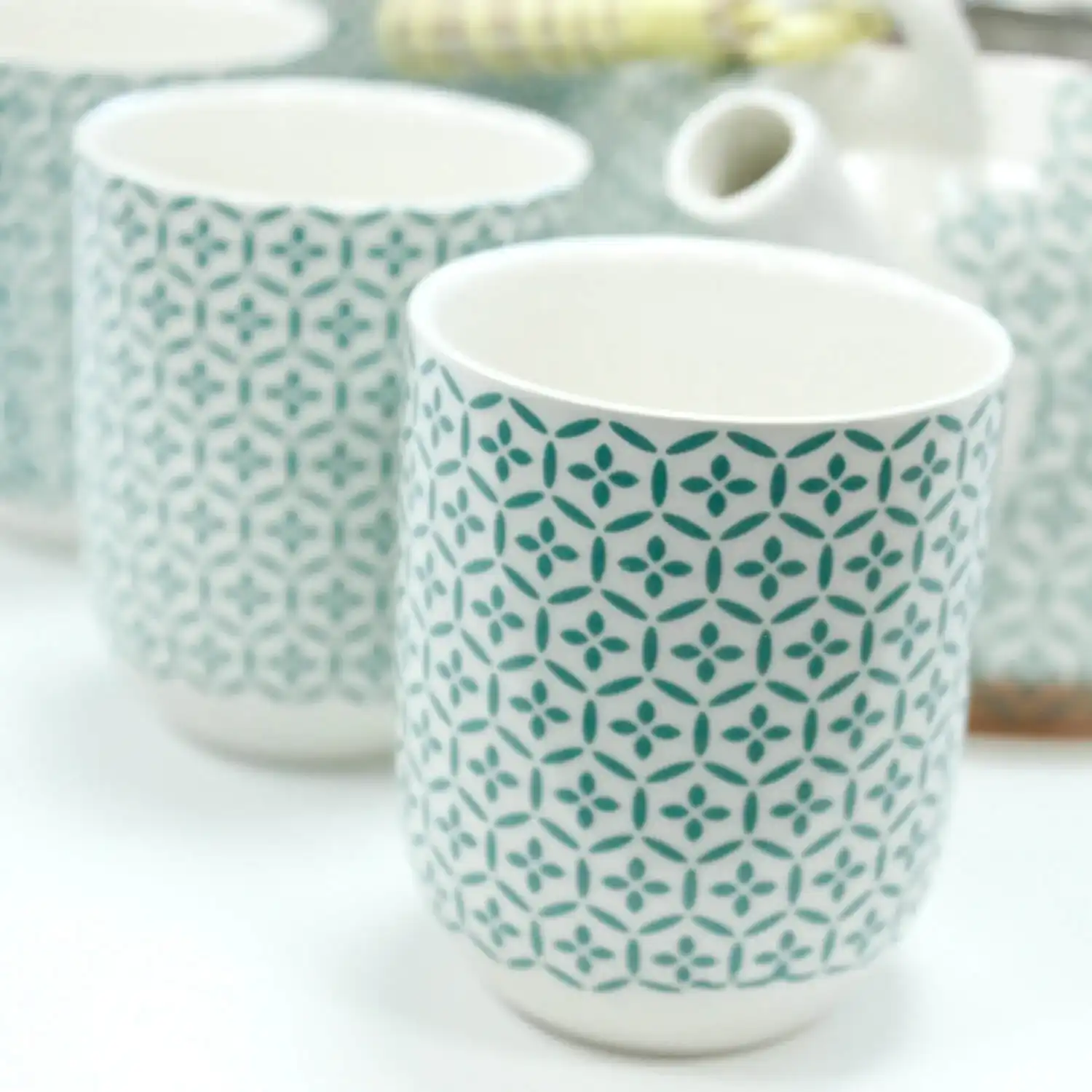 A close-up of patterned ceramic cups with a blue geometric design, arranged on a white surface.