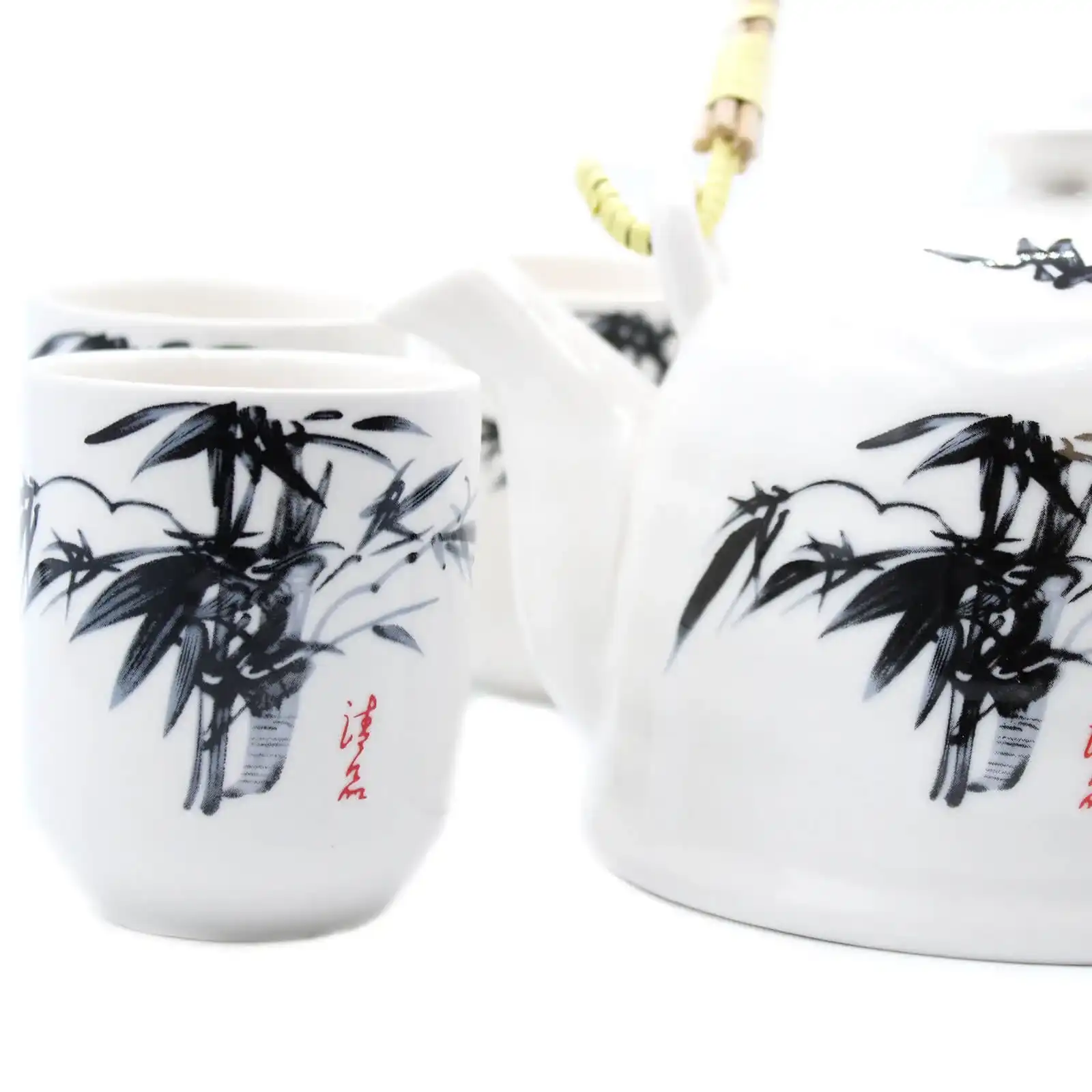 White porcelain teapot and cups with black bamboo design and red calligraphy, set on a white background.