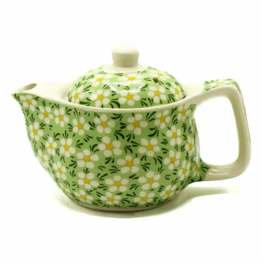 A ceramic teapot with a handle and spout, decorated with a green background and white and yellow floral pattern.