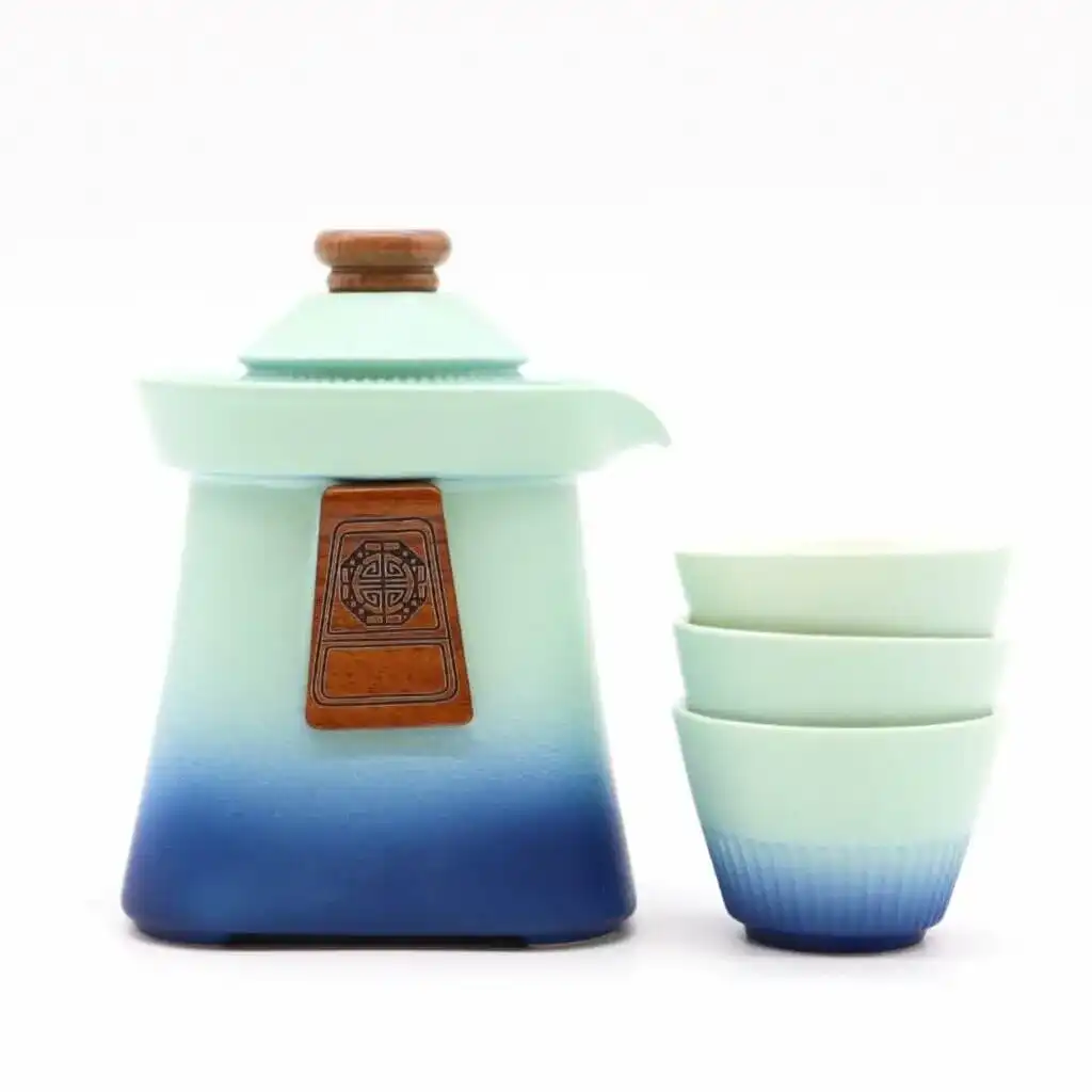A ceramic teapot with a wooden accent and three stacked matching teacups, all in a gradient blue and white design, set against a white background.