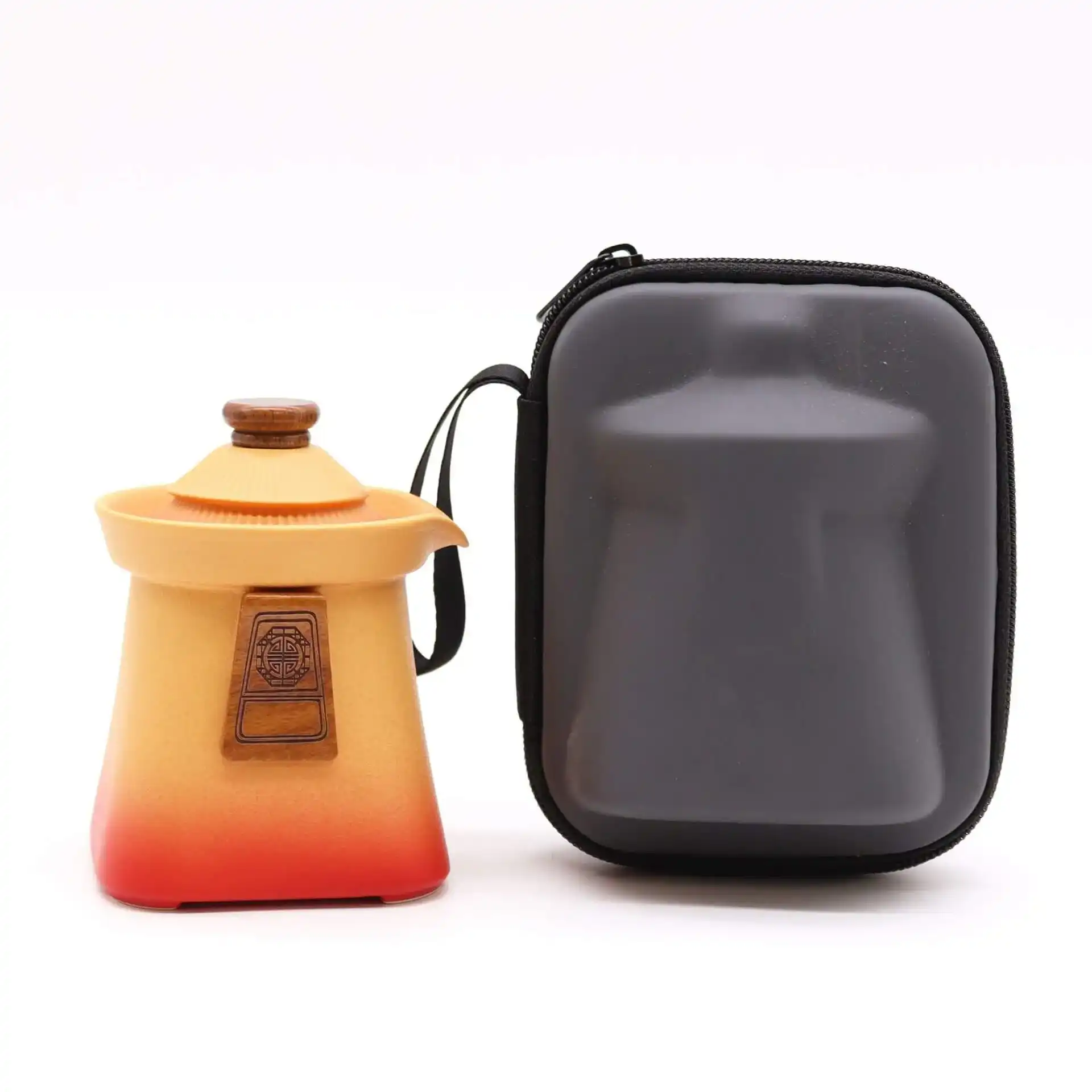 A small, gradient orange and red ceramic teapot with a lid is displayed next to a black, zippered carrying case shaped to fit the teapot.