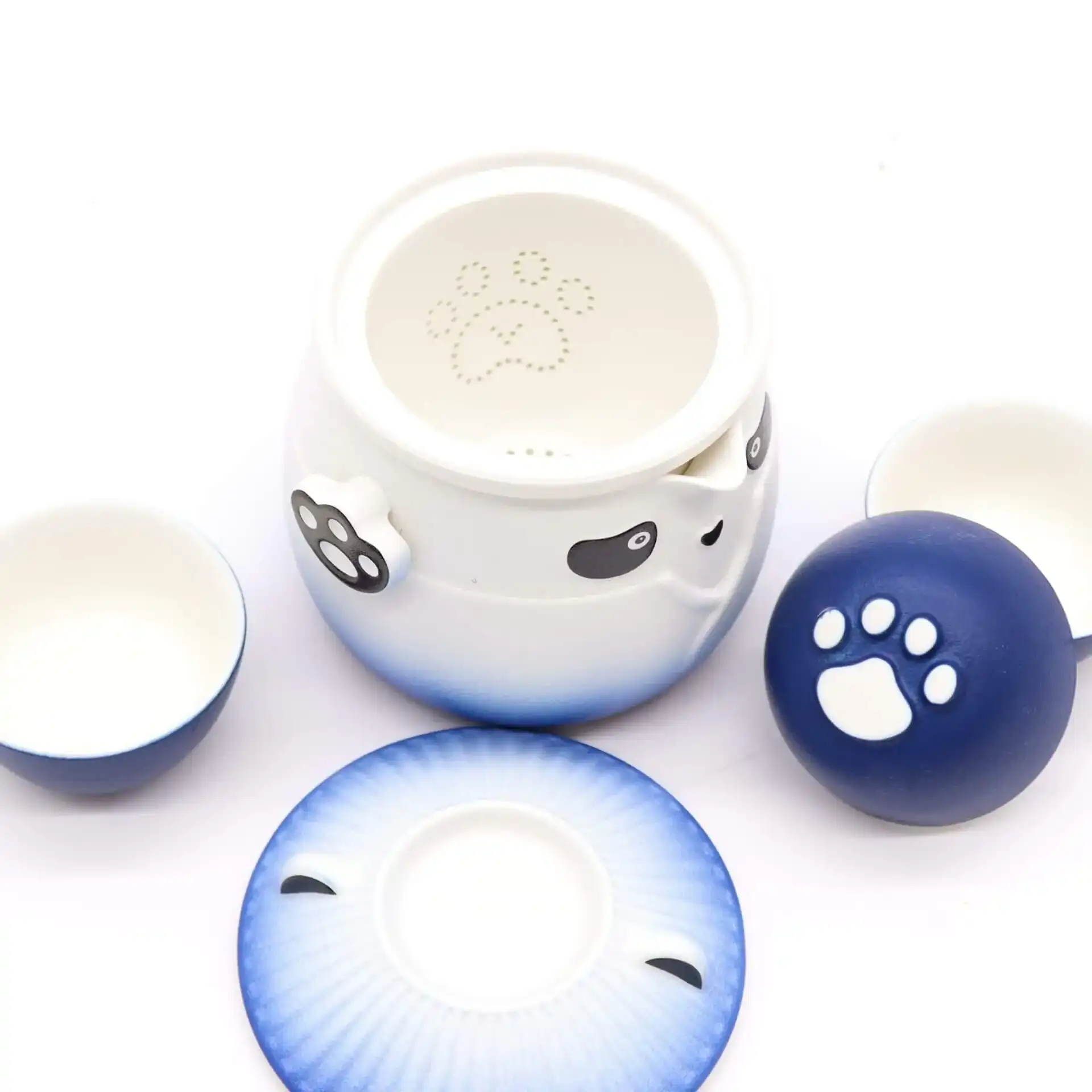 Ceramic tea set with panda and paw print designs, including a teapot, two cups, a lid, and a saucer, on a white background.