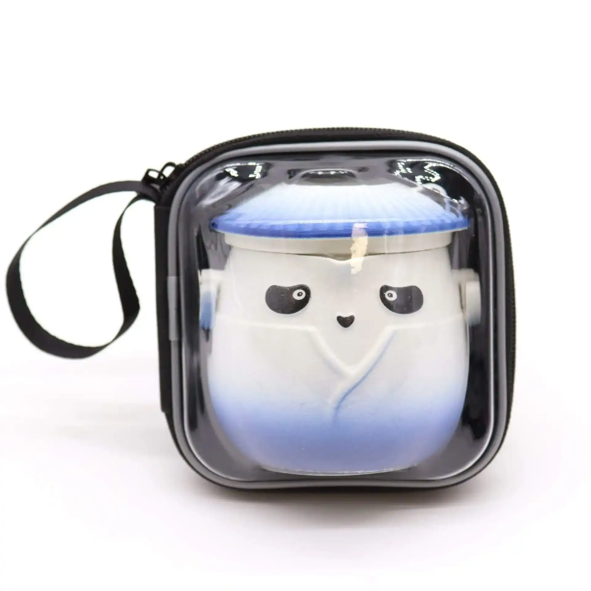 A small ceramic container with a face and blue gradient design, packaged in a square, clear zippered carrying case with a black handle.