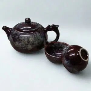 The Ocean Blue Teapot for One is an aqua teal tea set with 2 cups, featuring a glossy marbled finish and round lid, inspired by ocean hues, and elegantly displayed on a plain white background.