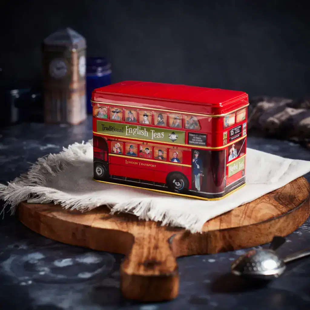 A Red London Bus Tea Tin - Traditional English Tea sits on a wooden board.