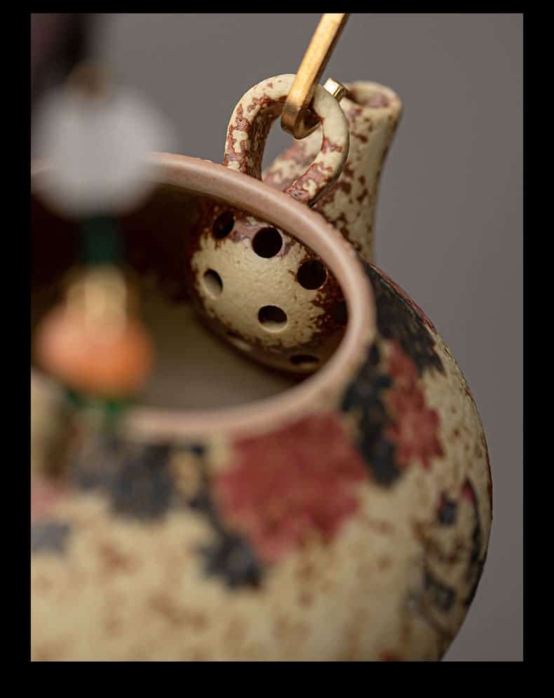 Close-up of the Whiskers & Blooms Hand-Painted Red Clay Ceramic Teapot-for-One (150ml), featuring a floral motif, with the spout strainer and part of the handle visible against a neutral background.