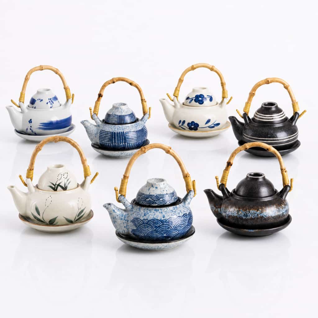 Seven 300ml Ceramic Teapot, Cup & Saucer Sets with bamboo handles—each showcasing unique patterns and vibrant colors—are displayed in two rows against a white background. The teapots hold 300ml each, making them ideal for enjoying your favorite tea with the matching cup and saucer set.