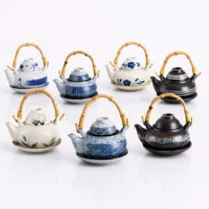 Seven 300ml Ceramic Teapot, Cup & Saucer Sets with bamboo handles—each showcasing unique patterns and vibrant colors—are displayed in two rows against a white background. The teapots hold 300ml each, making them ideal for enjoying your favorite tea with the matching cup and saucer set.
