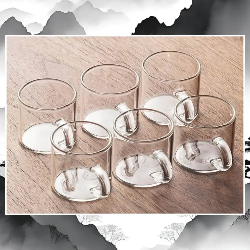 Two rows of six Master's Glass Kung Fu Tea Cups, featuring heat-resistant handles, are elegantly displayed on a wooden surface. Their transparent design is ideal for tea mastery.
