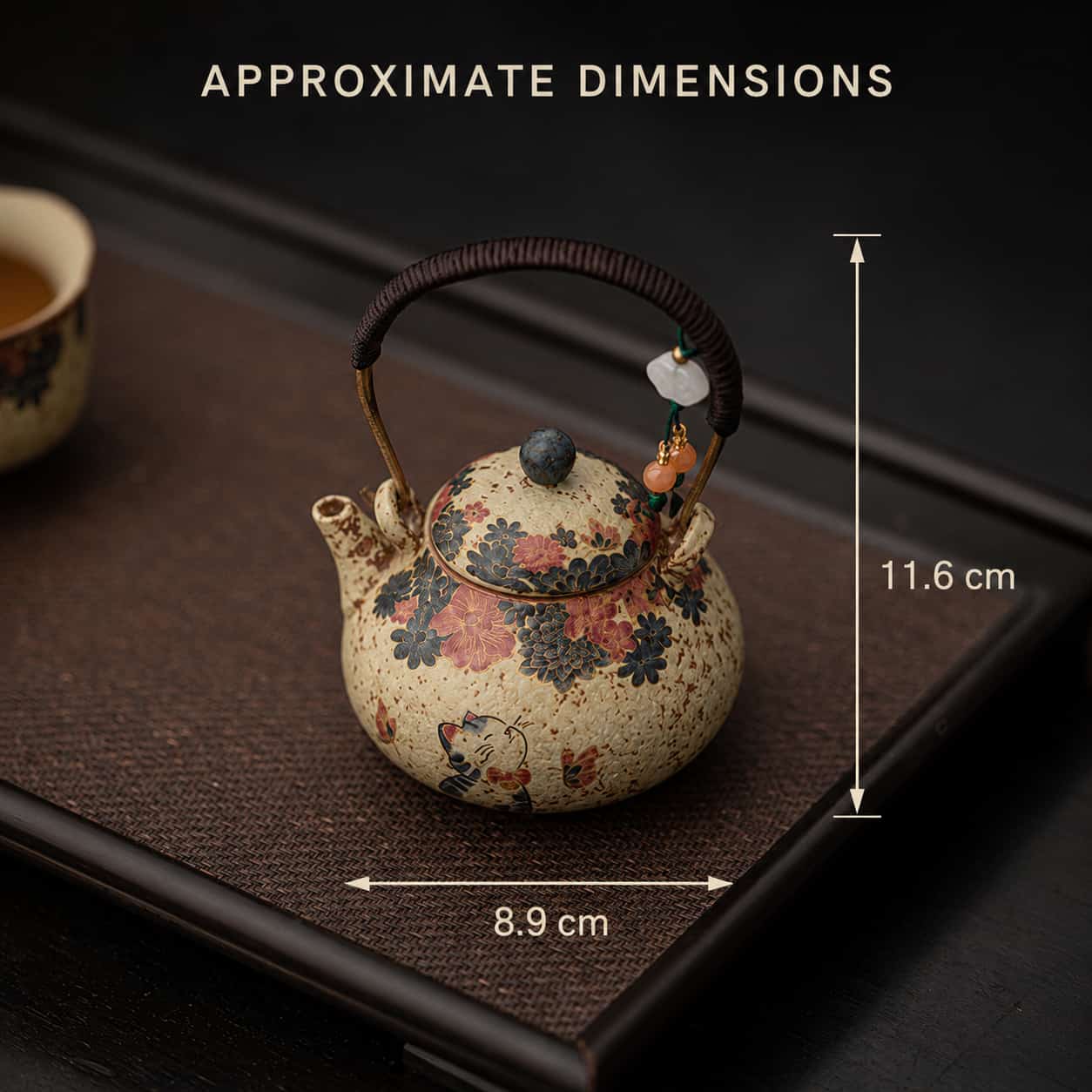 A Whiskers & Blooms Hand-Painted Red Clay Ceramic Teapot-for-One (150ml), adorned with floral patterns and featuring a delicate handle, is displayed on a tray. Its approximate dimensions are labelled: 8.9 cm wide and 11.6 cm tall.