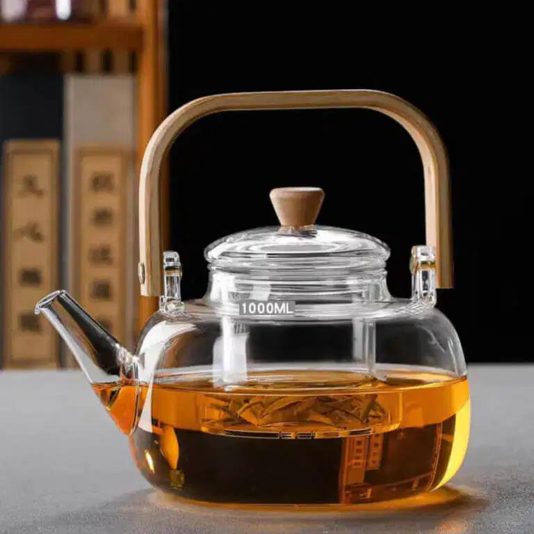 The Premium Glass Lifting Teapot, featuring a wooden handle and lid knob, is filled with amber Pu'er tea. The 1000ML heat-resistant kettle is set on a gray surface against a blurred background.