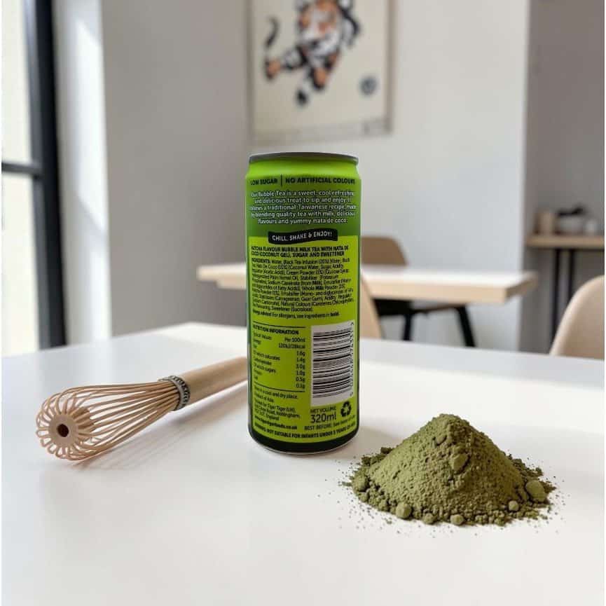 A can of matcha drink, a bamboo whisk, and a mound of matcha powder are arranged on a white table in a modern, minimalistic room.