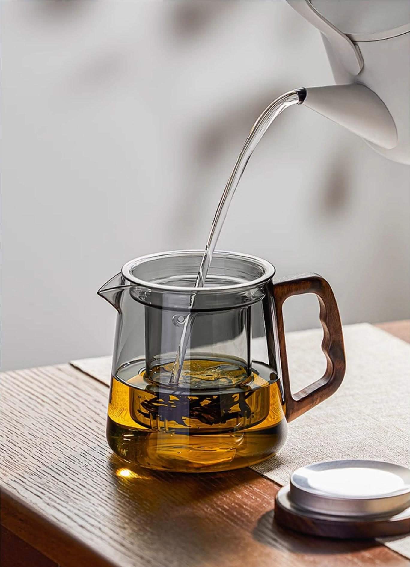 Hot water is poured from a kettle into a Borosilicate Glass Teapot with Glass Infuser & Walnut Handle, which features an internal tea infuser.