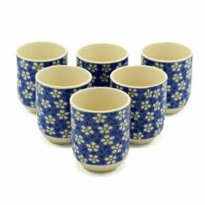 Six ceramic cups with a blue background and white floral pattern arranged in two rows on a white surface.