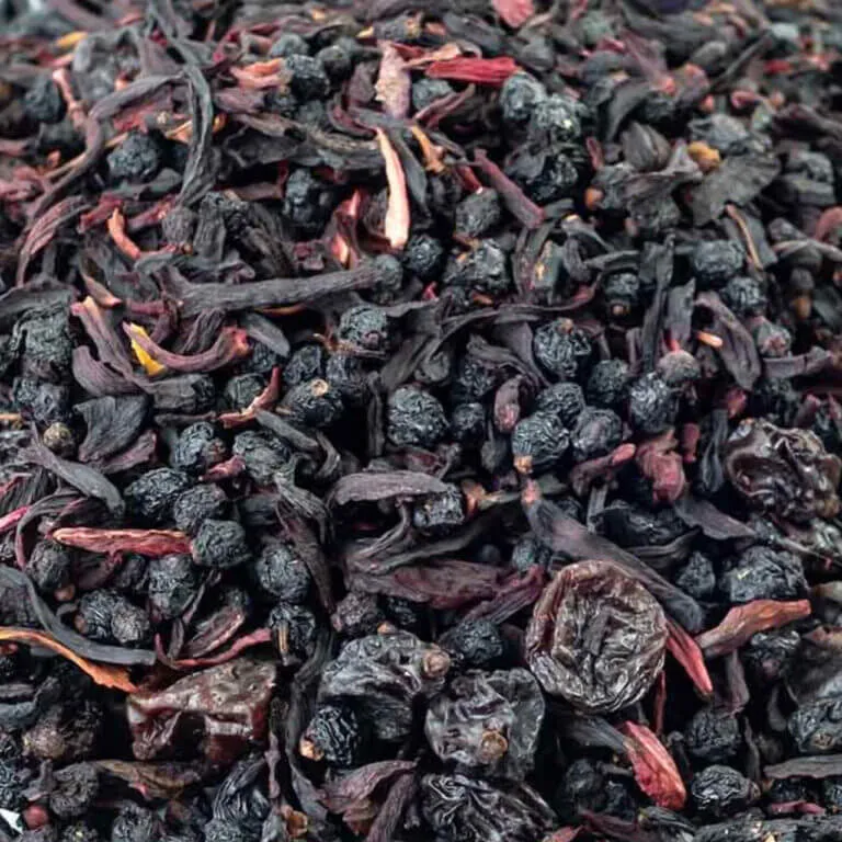 A close-up of dried hibiscus flowers and black currants, showcasing their dark red and black hues.